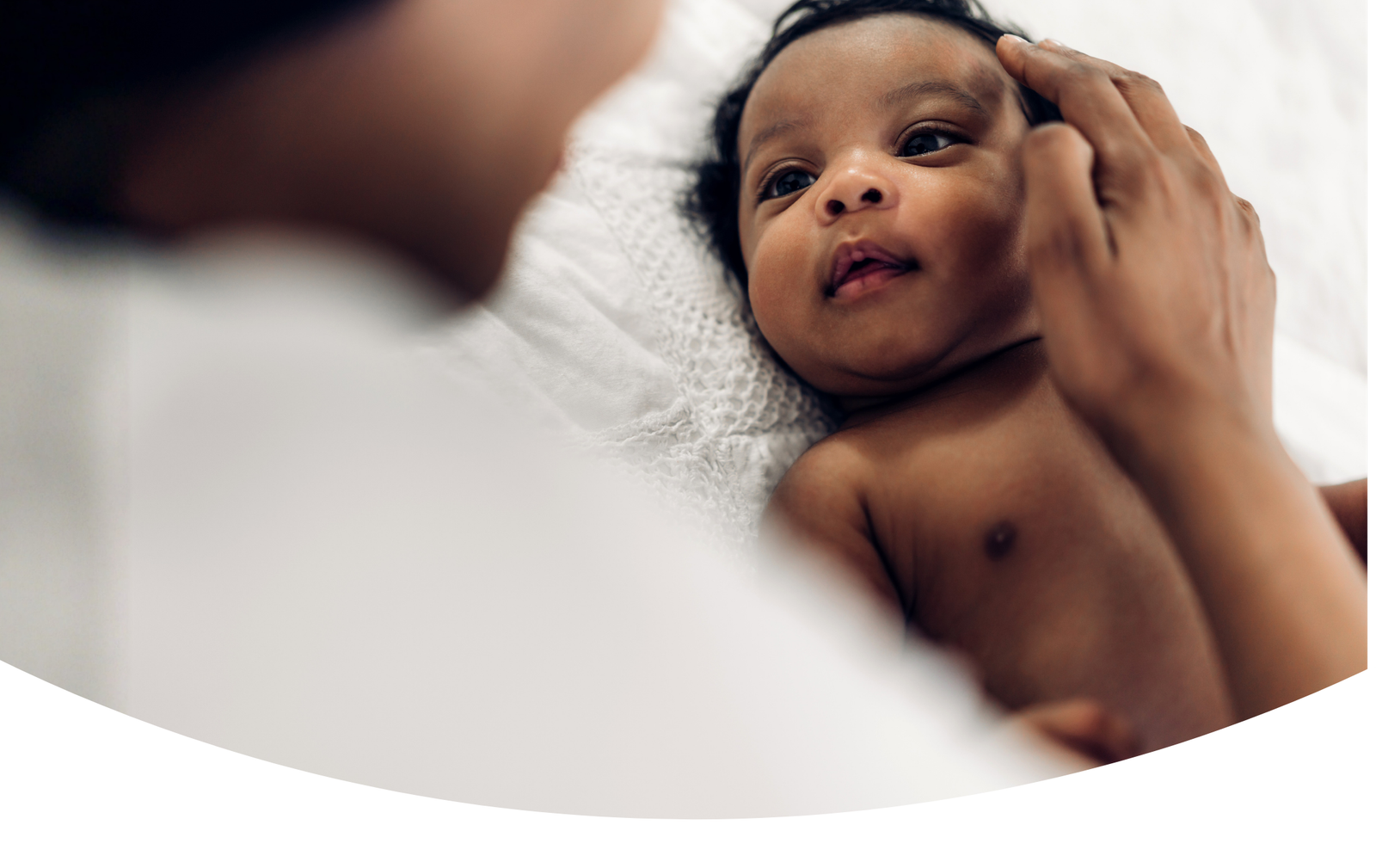 Bébé allongé recevant une caresse d’un parent